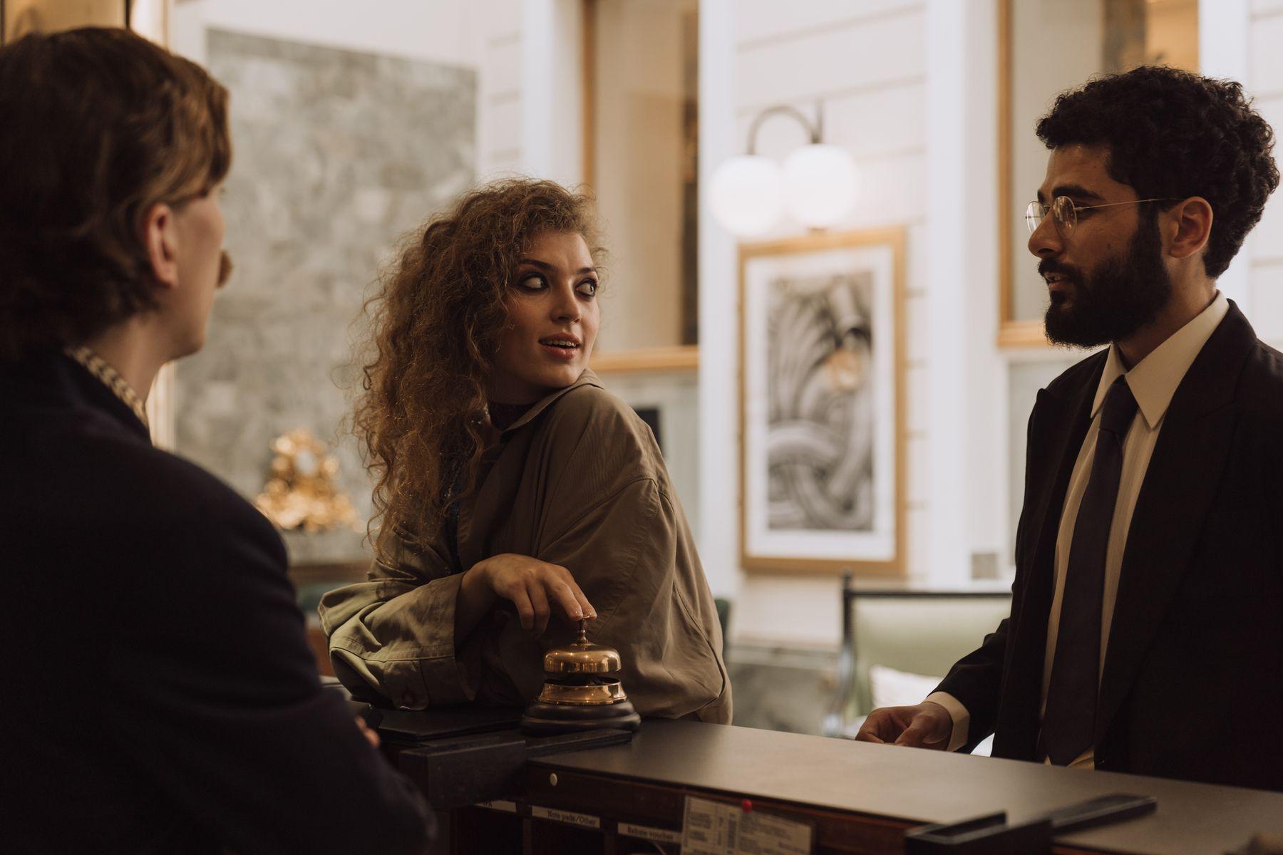 A hotel host chatting warmly with a guest, phone in hand